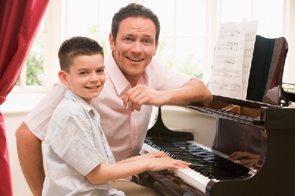 Man And Young Boy Playing Piano And Smiling